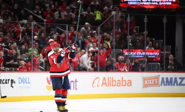 Washington Capitals left wing Alex Ovechkin (8) raises his stick to the crowd after he was recognized for playing in his 1,500th NHL hockey game during a break in the action in the first period against the Ottawa Senators, Saturday, Oct. 25, 2025, in Washington. (AP Photo/Nick Wass)
