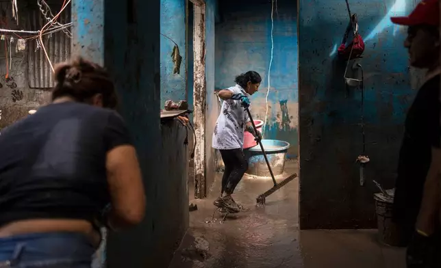 People clean the Olvera Gomez family's house in Poza Rica, Veracruz state, Mexico, Monday, Oct. 13, 2025, after torrential rains. (AP Photo/Felix Marquez)