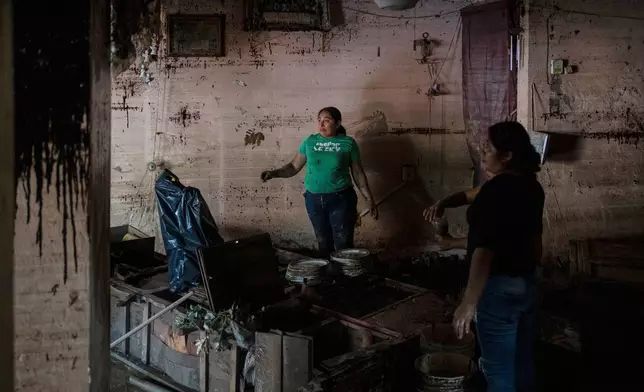 People clean the Ramirez family's flooded house in Poza Rica, Veracruz state, Mexico, Monday, Oct. 13, 2025, after torrential rains. (AP Photo/Felix Marquez)