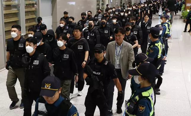 South Koreans, wearing caps, allegedly involved in online scams in Cambodia arrive at the Incheon International Airport, in Incheon, Saturday, Oct. 18, 2025. (Yonhap via AP)