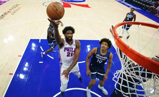 Philadelphia 76ers' Joel Embiid (21) goes up for a shot past Minnesota Timberwolves' Joan Beringer (19) during the first half of an preseason NBA basketball game Friday, Oct. 17, 2025, in Philadelphia. (AP Photo/Matt Slocum)