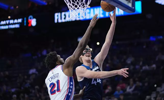 Minnesota Timberwolves' Rocco Zikarsky, right, goes up for a shot past Philadelphia 76ers' Joel Embiid during the first half of a preseason NBA basketball game Friday, Oct. 17, 2025, in Philadelphia. (AP Photo/Matt Slocum)