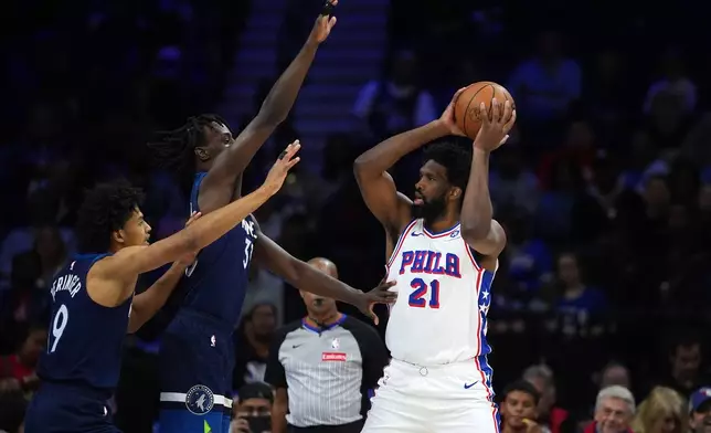 Philadelphia 76ers' Joel Embiid (21) tries to pass against Minnesota Timberwolves' Leonard Miller (33) and Joan Beringer (19) during the first half of a preseason NBA basketball game Friday, Oct. 17, 2025, in Philadelphia. (AP Photo/Matt Slocum)