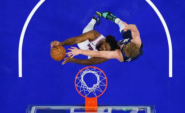 Philadelphia 76ers' Joel Embiid, left, cannot get a shot past Minnesota Timberwolves' Rocco Zikarsky during the first half of an preseason NBA basketball game Friday, Oct. 17, 2025, in Philadelphia. (AP Photo/Matt Slocum)