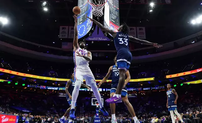 Philadelphia 76ers' Joel Embiid (21) goes up for a shot past Minnesota Timberwolves' Leonard Miller (33) during the first half of an preseason NBA basketball game Friday, Oct. 17, 2025, in Philadelphia. (AP Photo/Matt Slocum)