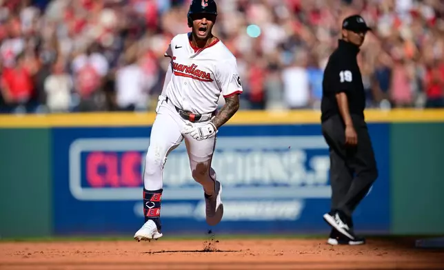 Cleveland Guardians Brayan Rocchio reacts as he rounds the bases after hitting a solo home run in the eighth inning of Game 2 of the American League Wild Card baseball playoff series against the Detroit Tigers in Cleveland, Wednesday, Oct. 1, 2025. Umpire Vic Carapazza looks on at right. (AP Photo/David Dermer)