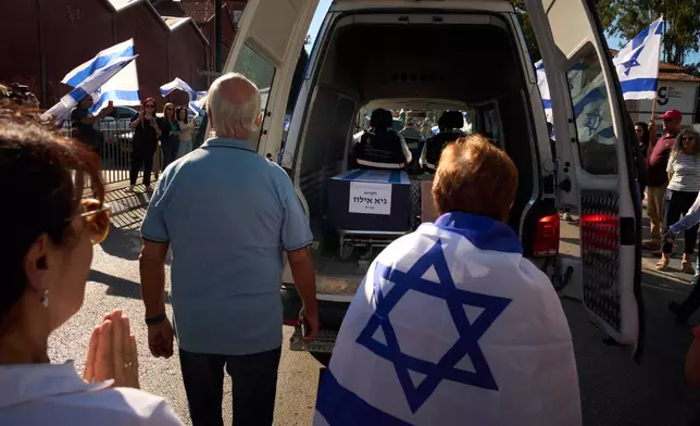 Mourners walk near the car carrying the coffin of slain hostage Guy Illouz during his funeral procession in Rishon Lezion, Israel, Wednesday, Oct. 15, 2025. Illouz remains were returned from Gaza to Israel as part of a ceasefire agreement between Israel and Hamas. (AP Photo/Emilio Morenatti)