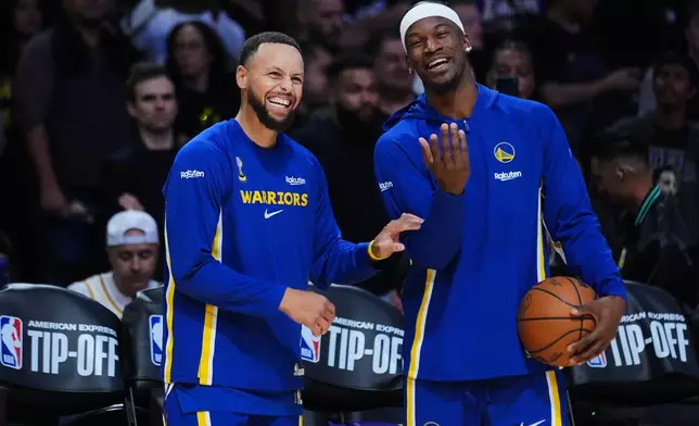 Golden State Warriors guard Stephen Curry, left, smiles next to forward Jimmy Butler III before an NBA basketball game against the Los Angeles Lakers Tuesday, Oct. 21, 2025, in Los Angeles. (AP Photo/Ethan Swope)