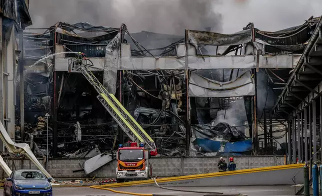 A firefighter works to extinguish a fire at a warehouse following a Russian attack, Saturday, Oct. 25, 2025, in Kyiv, Ukraine. (AP Photo/Julia Demaree Nikhinson)