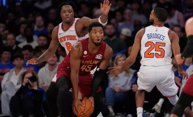 Cleveland Cavaliers' Donovan Mitchell (45) protects the ball from New York Knicks' Og Anunoby (8) and Mikal Bridges (25) during the second half of an NBA basketball game Wednesday, Oct. 22, 2025, at Madison Square Garden in New York. (AP Photo/Frank Franklin II)