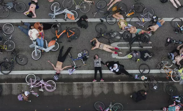 EDS NOTE: NUDITY - Cyclists in the Naked Bike Ride lay down in protest against Donald Trump's attempts to mobilize the National Guard on the Burnside Bridge, Sunday, Oct. 12, 2025, in Portland, Ore. (AP Photo/Jenny Kane)