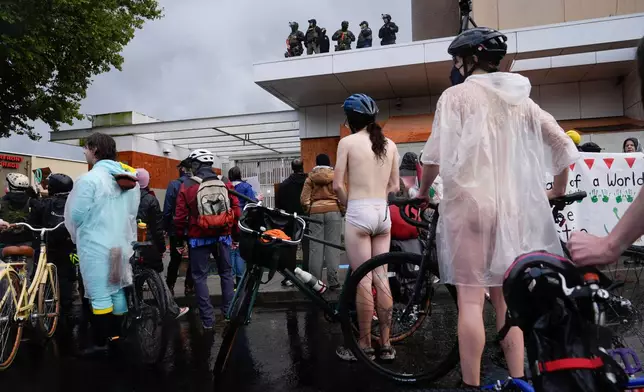 Federal agents stand and look over protesters during the Naked Bike Ride protest at the U.S. Immigration and Customs Enforcement facility on Sunday, Oct. 12, 2025, in Portland, Ore. (AP Photo/Jenny Kane)