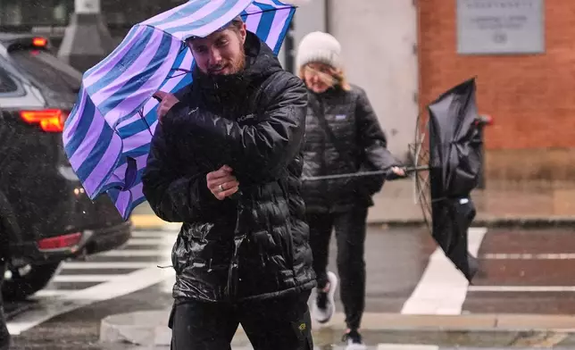 Two people battle gusts with their umbrellas as they fight a wind-driven rain storm, Monday, Oct. 13, 2025, in Boston. (AP Photo/Charles Krupa)