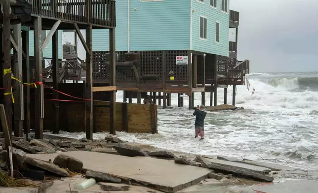 A homeowner takes a photo after a storm, Monday, Oct. 13, 2025, in Buxton, N.C. (AP Photo/Allison Joyce)