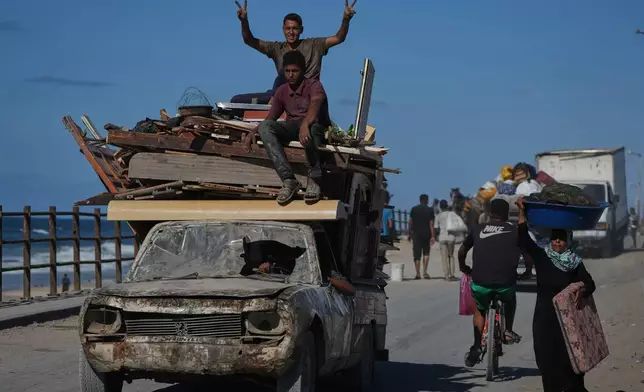A displaced Palestinian flashes a V-sign to the camera while fleeing northern Gaza along the coastal road near Wadi Gaza, Wednesday, Oct, 1, 2025. (AP Photo/Abdel Kareem Hana)
