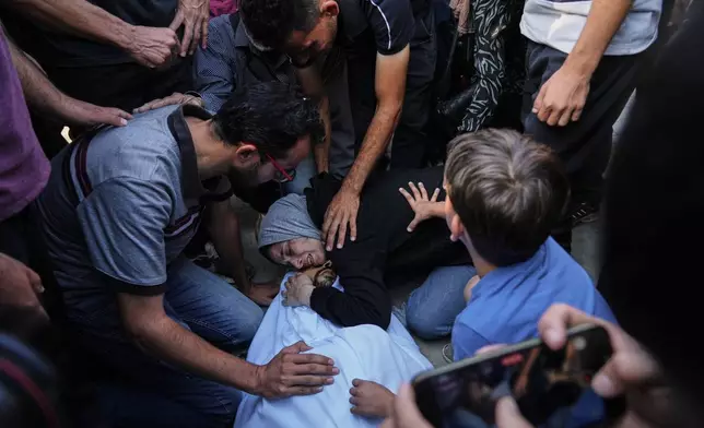 Nahrawan Al-Khatib bids farewell to her husband, Yahya Barzaq, who was killed in an Israeli strike on Deir al-Balah, Gaza Strip, Wednesday, Oct. 1, 2025. (AP Photo/Abdel Kareem Hana)