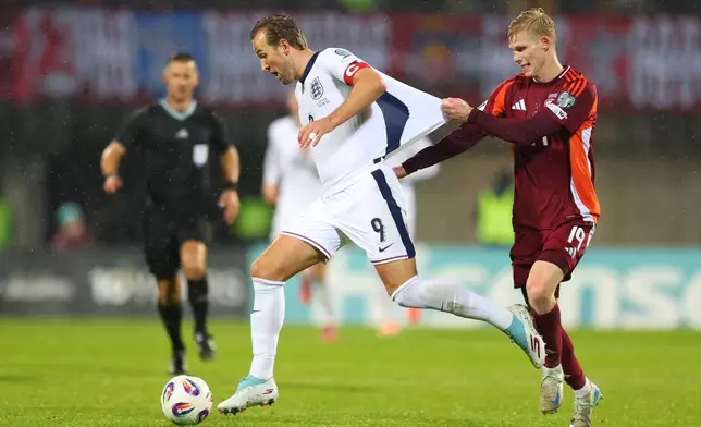 Latvia's Maksims Tonisevs, right, pulls the shirt of England's Harry Kane during the 2026 World Cup group K qualifying soccer match between Latvia and England in Riga, Latvia, Tuesday, Oct. 14, 2025. (AP Photo/Roman Koksarov)