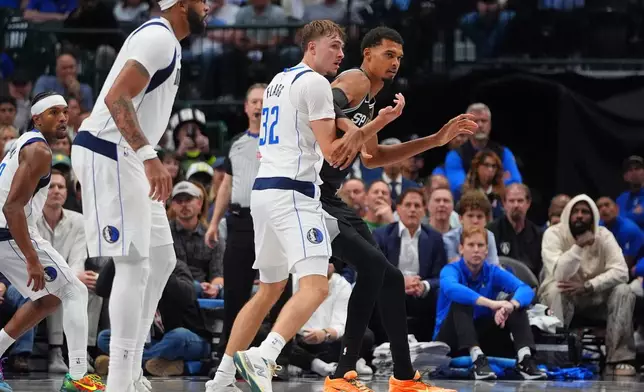 San Antonio Spurs forward Victor Wembanyama, right, is defended by Dallas Mavericks forward Cooper Flagg (32) as forward Anthony Davis, second from left, looks on during the second half of an NBA basketball game in Dallas, Wednesday, Oct. 22, 2025. (AP Photo/LM Otero)