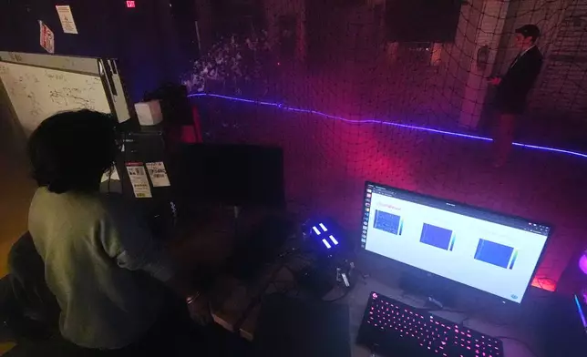 Colin Balfour, a sophomore studying robotics engineering, right, flies a small drone through a simulated snowstorm at night at a laboratory at the Worcester Polytechnic Institute, Monday, Oct. 20, 2025, in Worcester, Mass. (AP Photo/Charles Krupa)