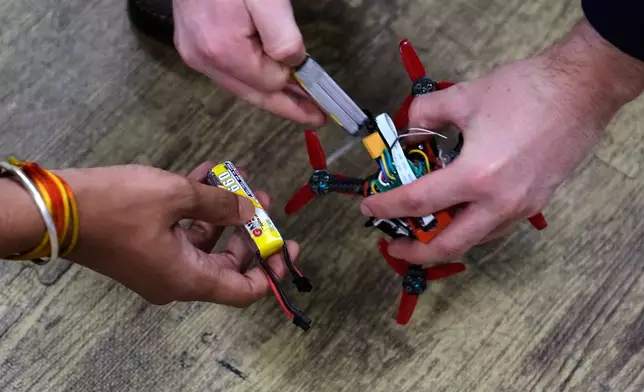 Robotics engineering students change out the battery on a tiny drone at a laboratory at Worcester Polytechnic Institute, Monday, Oct. 20, 2025, in Worcester, Mass. (AP Photo/Charles Krupa)