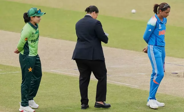 India's captain Harmanpreet Kaur, right, and Pakistan's captain Fatima Sana proceed for coin toss before the ICC Women's Cricket World Cup match between India and Pakistan at Premadasa Stadium in Colombo, Sri Lanka, Sunday, Oct, 5, 2025. (AP Photo/Eranga Jayawardena)