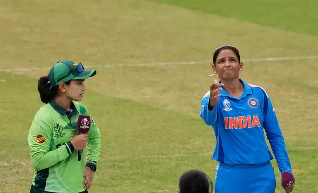 India's captain Harmanpreet Kaur, right, tosses a coin as Pakistan's captain Fatima Sana watches before the ICC Women's Cricket World Cup match between India and Pakistan at Premadasa Stadium in Colombo, Sri Lanka, Sunday, Oct, 5, 2025. (AP Photo/Eranga Jayawardena)