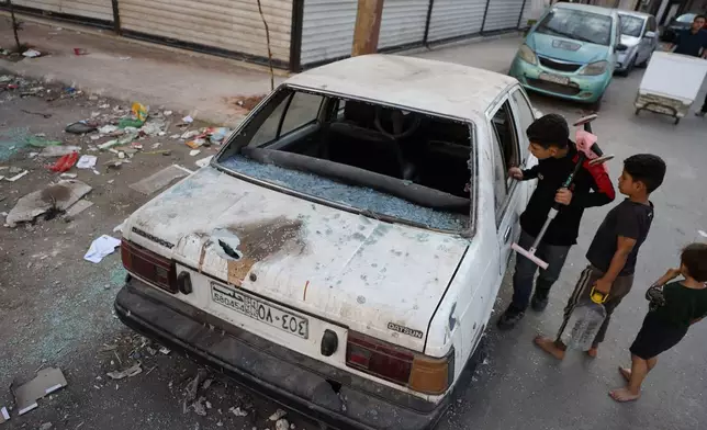 Children look at a damaged car in the Saif al-Dawla district of Aleppo, Syria, Tuesday, Oct. 7, 2025, following overnight clashes between Syrian government troops and the Kurdish-led Syrian Democratic Forces. (AP Photo/Omar Albam)
