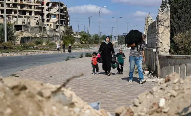Residents leave the Sheikh Maqsoud and Achrafieh neighborhoods of Aleppo, Syria, Tuesday, Oct. 7, 2025, following overnight clashes between Syrian government troops and the Kurdish-led Syrian Democratic Forces. (AP Photo/Omar Albam)