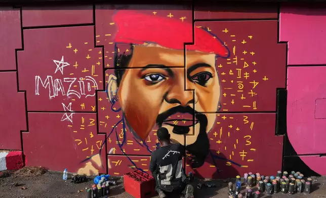 Graffiti artist Omar Diaw works on a mural depicting Guinea's President Mamadi Doumbouya on a street wall in Conakry, Guinea, Saturday, Sep. 20, 2025. (AP Photo/Misper Apawu)