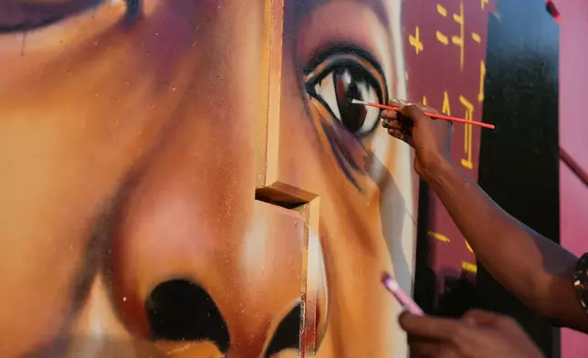 Graffiti artist Omar Diaw paints details on a mural depicting Guinea's President Mamadi Doumbouya in Conakry, Guinea, Saturday, Sep. 20, 2025. (AP Photo/Misper Apawu)