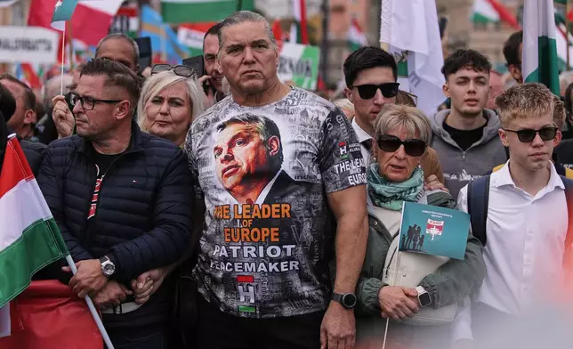 A man wearing a T-shirt with Hungarian Prime Minister Viktor Orban attends a pro-government march marking the 69th anniversary of the outbreak of Hungary's 1956 revolution against communist rule and the Soviet Union, in Budapest, Hungary, Thursday, Oct. 23, 2025. (AP Photo/Rudolf Karancsi)