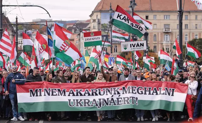Pro-government demonstrators hold a banner reading "We don't want to die for Ukraine!" in Hungarian during celebrations marking the 69th anniversary of the outbreak of Hungary's 1956 revolution against communist rule and the Soviet Union, in Budapest, Hungary, Thursday, Oct. 23, 2025. (AP Photo/Rudolf Karancsi)