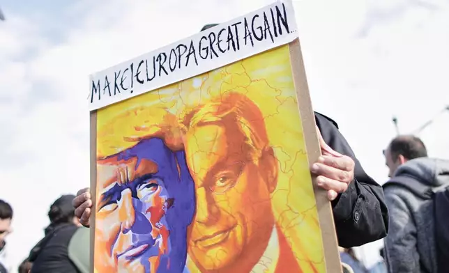 A pro-government demonstrator holds a sign with drawings of U.S. President Donald Trump and Hungarian Prime Minister Viktor Orban during celebrations marking the 69th anniversary of the outbreak of Hungary's 1956 revolution against communist rule and the Soviet Union, in Budapest, Hungary, Thursday, Oct. 23, 2025. (AP Photo/Rudolf Karancsi)