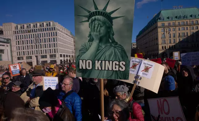 A woman displays a "No Kings" sign as she participates in a pro-democracy, anti-Trump protest outside the US embassy at the Pariser Platz square in Berlin, Saturday, Oct. 18, 2025. (AP Photo/Markus Schreiber)
