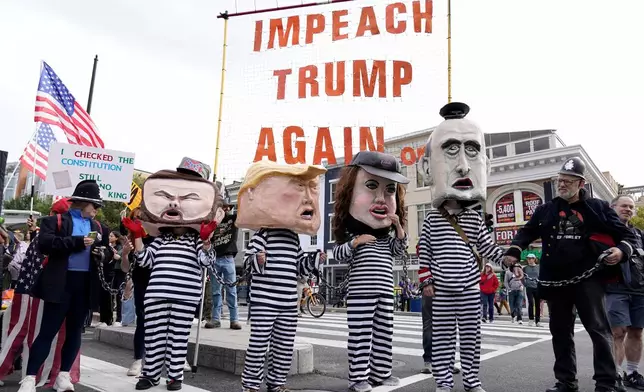 Demonstrators wear costumes and carry signs as they rally at the 14th and U street corridor before marching to the national Mall during a No Kings protest in Washington, Saturday, Oct. 18, 2025. (AP Photo/Jose Luis Magana)