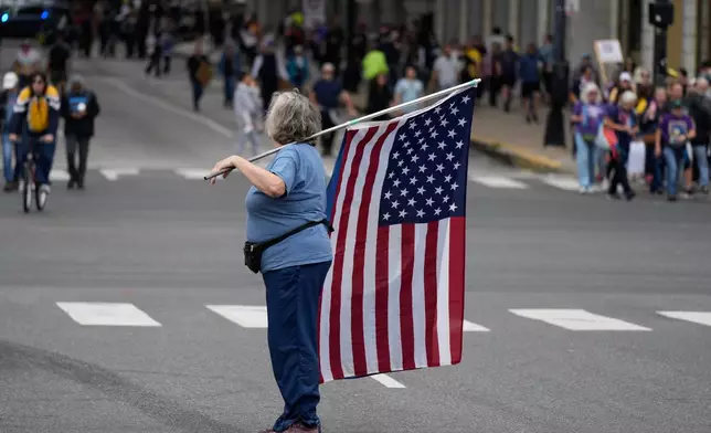 A person holds an American flag before a "No Kings" protest Saturday, Oct. 18, 2025, in Chicago. (AP Photo/Nam Y. Huh)
