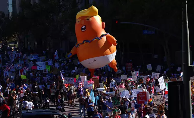 Pulling a giant inflatable Donald Trump protesters march in the streets during a "No Kings" protest Saturday, Oct. 18, 2025, in Los Angeles. (AP Photo/Ethan Swope)