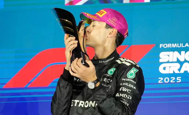 Mercedes driver George Russell of Britain kisses his trophy as he celebrates after winning the Singapore Formula One Grand Prix at the Marina Bay Street Circuit in Singapore, Sunday, Oct. 5, 2025. (AP Photo/Vincent Thian)