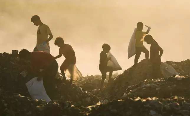 Displaced Palestinian children search for firewood and plastic in a landfill beside the makeshift tent camp where they are taking shelter, in Khan Younis, southern Gaza Strip, Tuesday, Sept. 30, 2025. (AP Photo/Jehad Alshrafi)