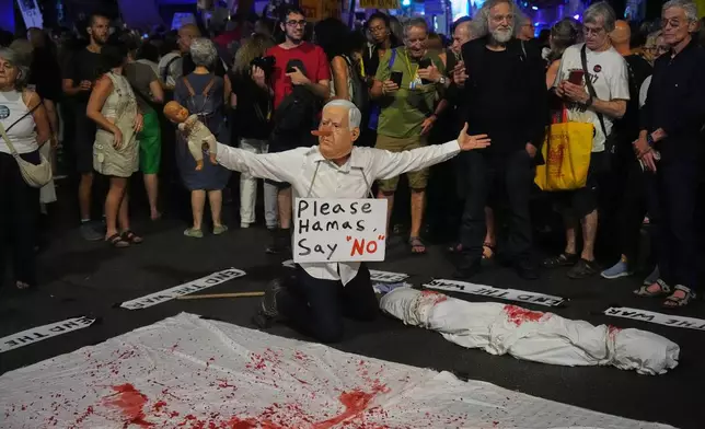 A demonstrator wears a mask depicting Israeli Prime Minister Benjamin Netanyahu during a protest calling for the immediate release of all hostages held by Hamas in the Gaza Strip and an end to the ongoing war, in Tel Aviv, Israel, Tuesday, Sept. 30, 2025, (AP Photo/Ariel Schalit)