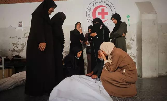 Mourners gather around the bodies of Palestinians, killed by Israeli fire after crossing the ceasefire line according to the Hamas-run Civil Defense, as they brought to Al Ahli Hospital in Gaza City, Saturday, Oct. 18, 2025. (AP Photo/Yousef Al Zanoun)