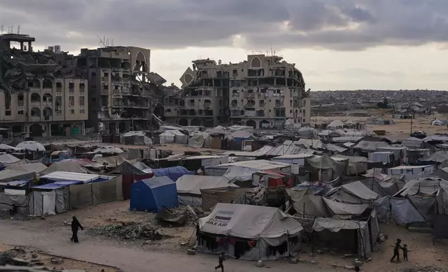 A tent camp for displaced Palestinians sits adjacent to destroyed homes and buildings in Khan Younis, Gaza Strip, Saturday, Oct. 18, 2025. (AP Photo/Jehad Alshrafi)