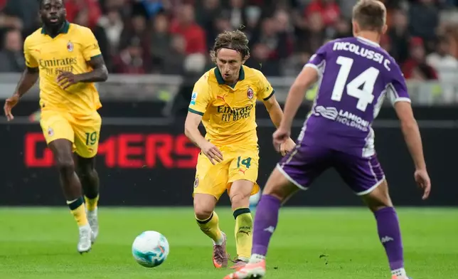 AC Milan's Luka Modric, center, pases the ball past Fiorentina's Hans Nicolussi Caviglia during a Serie A soccer match between AC Milan and Fiorentina in Milan, Italy, Sunday, Oct. 19, 2025. (AP Photo/Luca Bruno)