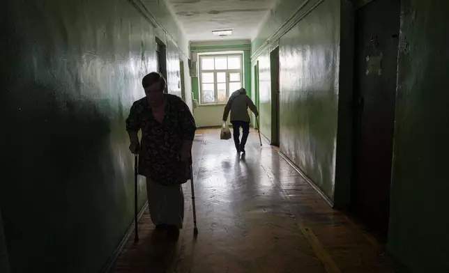 Elderly women walk in a corridor at a hostel for the displaced in Dnipro, Ukraine, Wednesday, Oct. 8, 2025. (AP Photo/Evgeniy Maloletka)