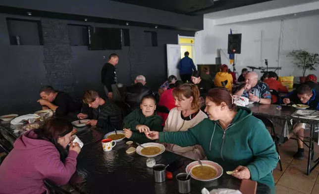 People eat at a hostel for the displaced in Dnipro, Ukraine, Wednesday, Oct. 8, 2025. (AP Photo/Evgeniy Maloletka)