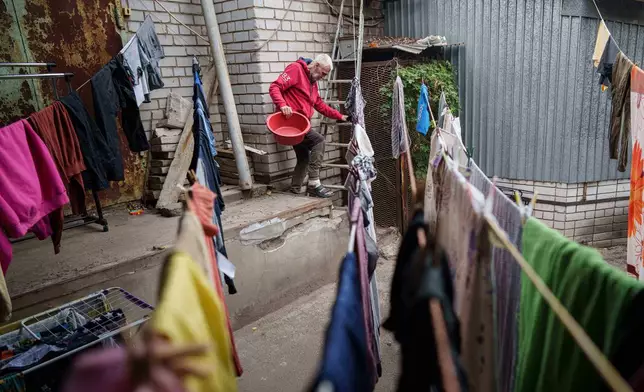 A man works to dry washed clothing at a hostel for the displaced in Dnipro, Ukraine, Wednesday, Oct. 8, 2025. (AP Photo/Evgeniy Maloletka)