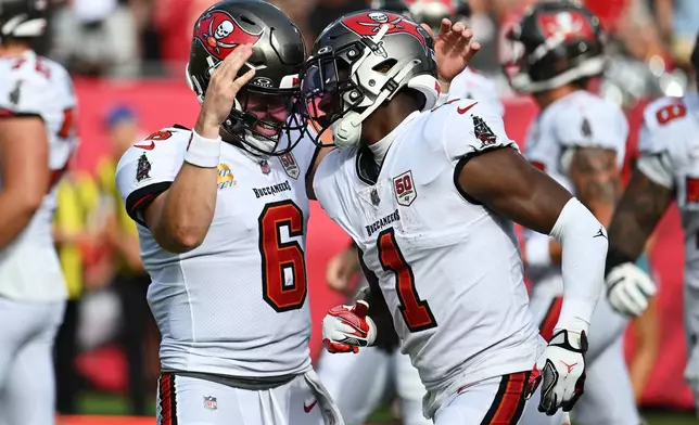 Tampa Bay Buccaneers running back Rachaad White (1) is congratulated by quarterback Baker Mayfield (6) after scoring against the San Francisco 49ers during the first half of an NFL football game in Tampa, Fla., Sunday, Oct. 12, 2025. (AP Photo/Jason Behnken)