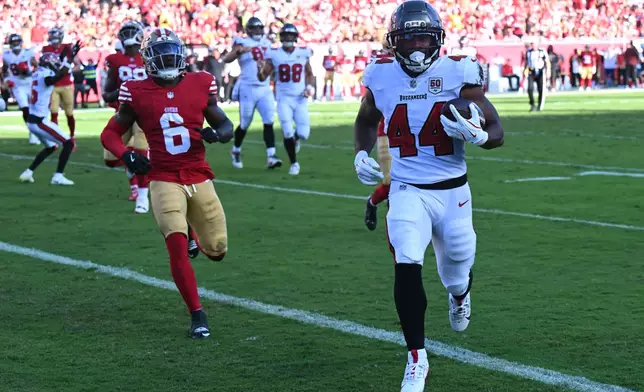Tampa Bay Buccaneers running back Sean Tucker (44) runs for a touchdown past San Francisco 49ers safety Malik Mustapha (6) during the first half of an NFL football game in Tampa, Fla., Sunday, Oct. 12, 2025. (AP Photo/Jason Behnken)
