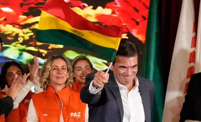 Presidential candidate Rodrigo Paz waves a Bolivian flag after preliminary results showed him leading in the presidential runoff election in La Paz, Bolivia, Sunday, Oct. 19, 2025. (AP Photo/Natacha Pisarenko)
