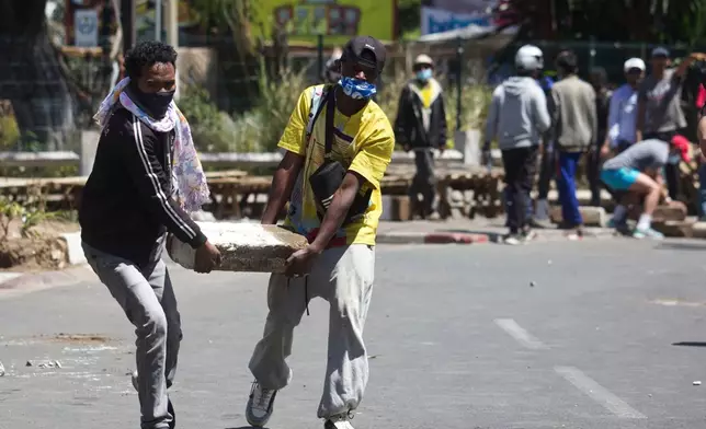 Protesters carry a concrete slab to help barricade the street during a protest calling for the president to step down in Antananarivo, Madagascar, Thursday, Oct. 9, 2025. (AP Photo/Alexander Joe)